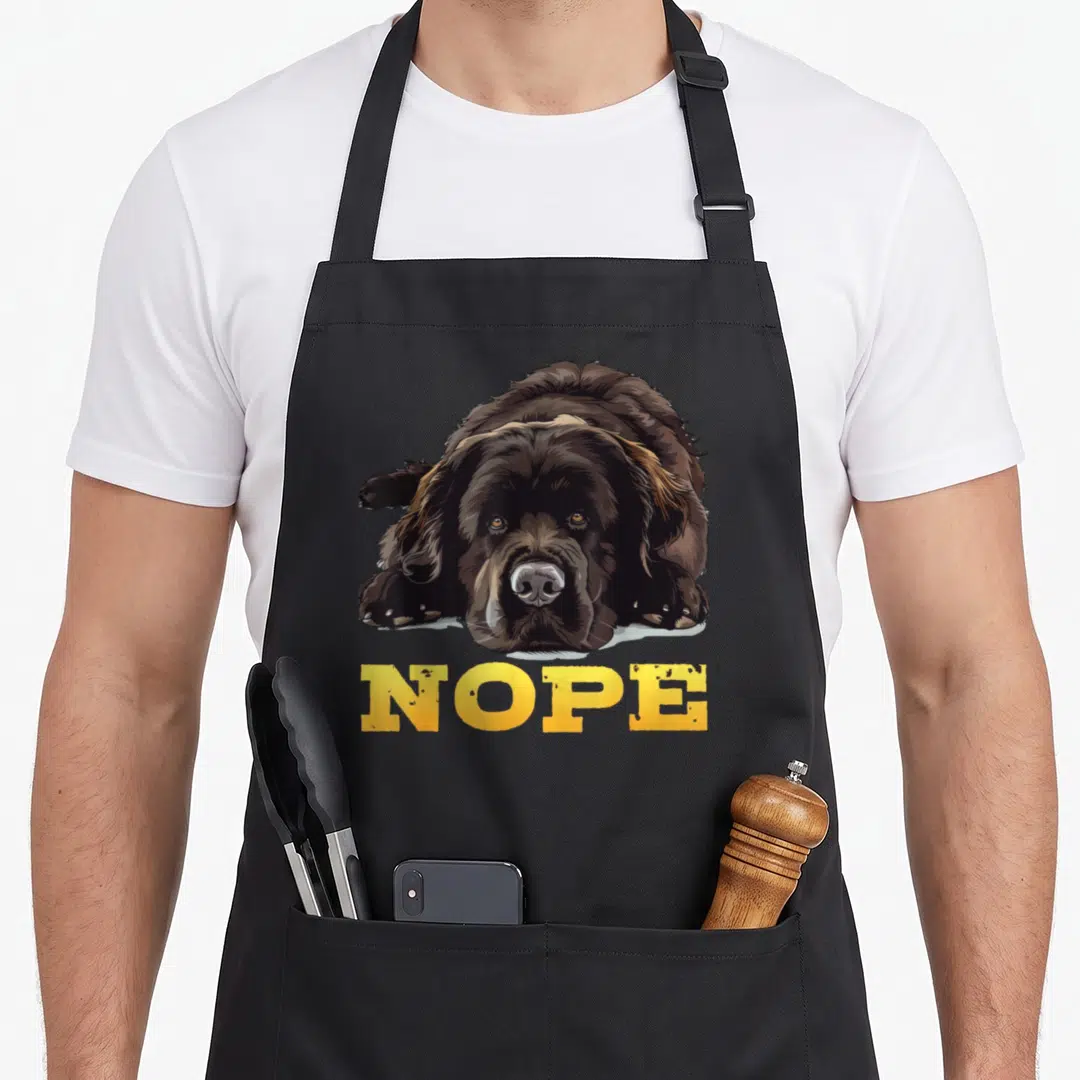 Newfoundland nope dog apron - Brown dog lying down facing forward with yellow NOPE text below — shown on a black cotton canvas apron against a white background