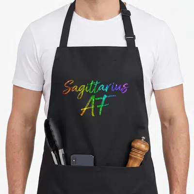 November december sagittarius birthday apron - Rainbow glitter cursive text reading Sagittarius AF stacked vertically — shown on a black cotton canvas apron against a white background