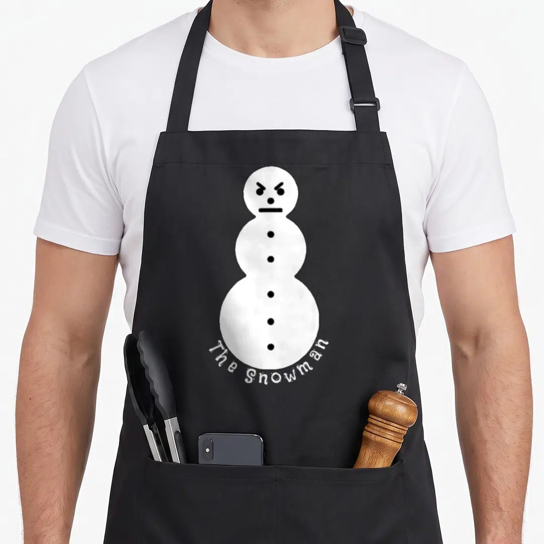 Feature snowman apron - Angry white snowman with black buttons and curved text reading The Snowman — shown on a black cotton canvas apron against a white background