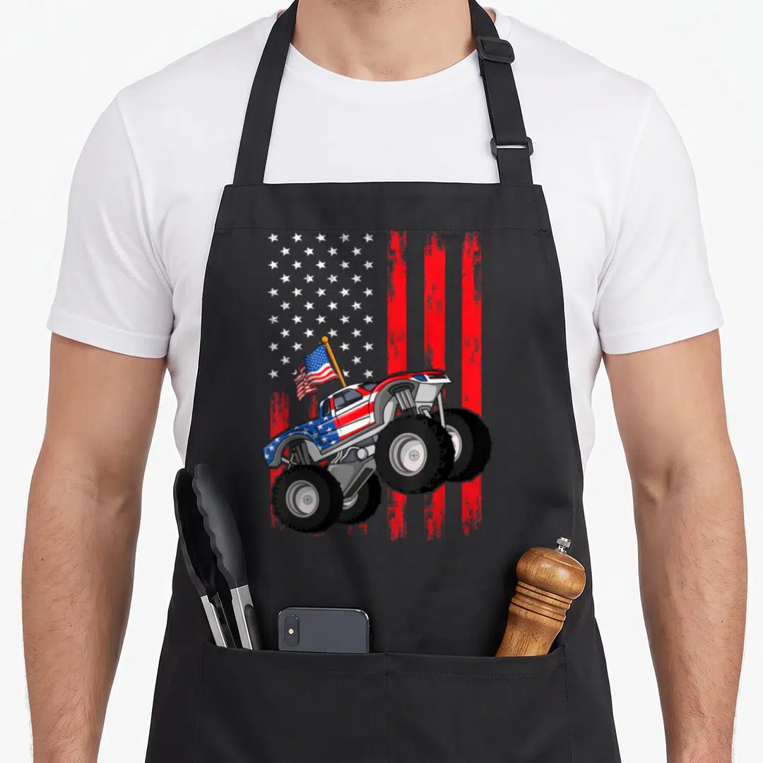 July truck aprons - Cartoon monster truck with US flag paint job in front of distressed stars and stripes — shown on a black cotton canvas apron against a white background