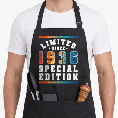 Limited edition special aprons - Stacked text Limited Since 1936 Special Edition with multi-colored distressed blocks — shown on a black cotton canvas apron against a white background