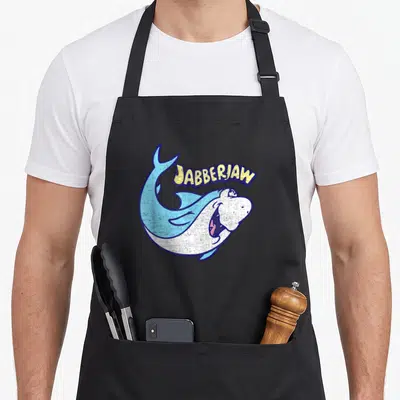 Jabberjaw barbera apron - Arched JABBERJAW text above a blue and white cartoon shark in a C-shape pose — shown on a black cotton canvas apron against a white background