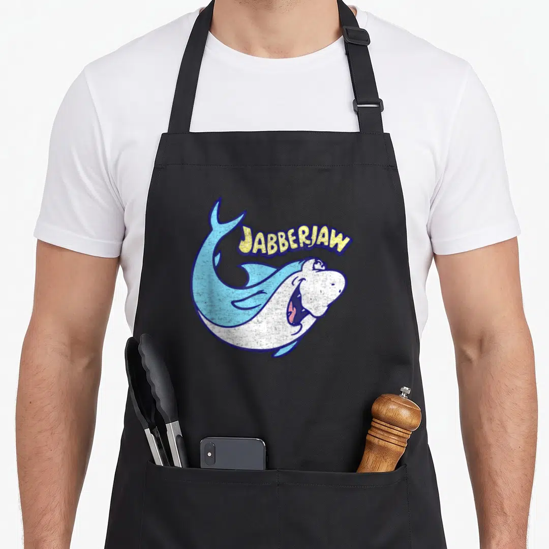 Jabberjaw barbera apron - Arched JABBERJAW text above a blue and white cartoon shark in a C-shape pose — shown on a black cotton canvas apron against a white background