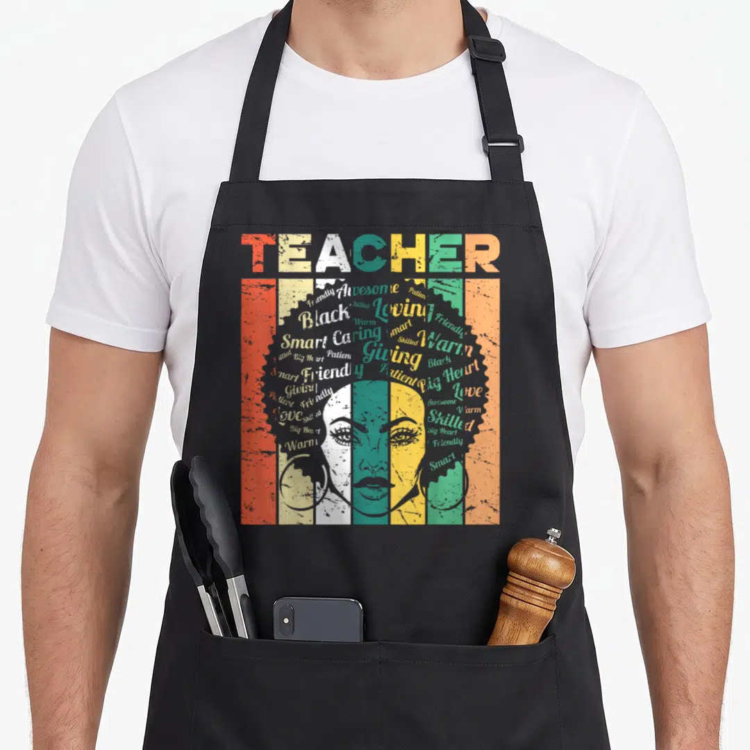 Afro teacher apron - Distressed woman face with striped afro made of positive adjectives like Smart and Loving in red — shown on a black cotton canvas apron against a white background