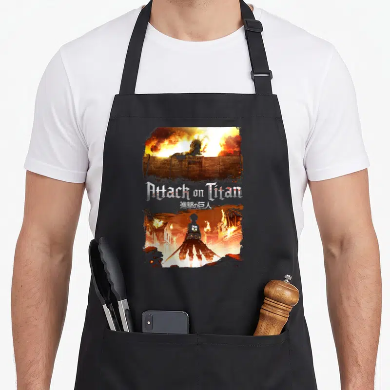 Key anime apron - Titan over wall and soldier silhouette in burning city with Attack on Titan text — shown on a black cotton canvas apron against a white background