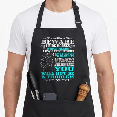 Beware horse apron - White and cyan stacked text reading beware I ride horses with horse head silhouette — shown on a black cotton canvas apron against a white background