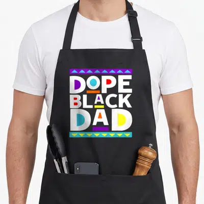 African father day apron - Stacked white Dope Black Dad text with colorful geometric shapes and purple blue patterned — shown on a black cotton canvas apron against a white background