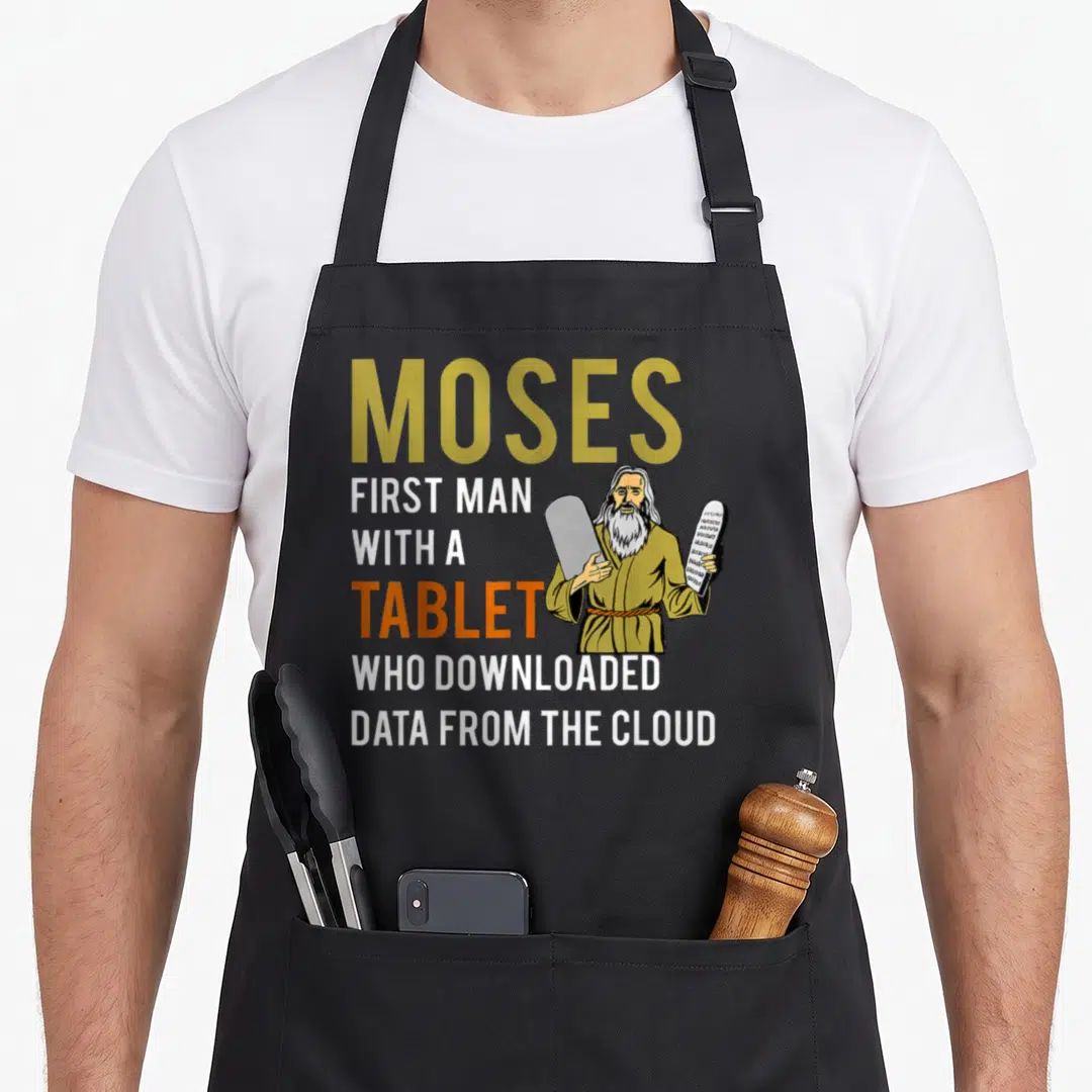 Mose passover apron - Cartoon Moses holding two tablets next to text about downloading data from the cloud — shown on a black cotton canvas apron against a white background