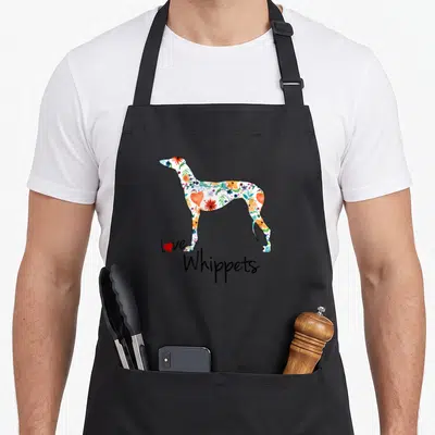 Vintage whippet apron - Floral whippet silhouette with Love Whippets text and red heart on black bib — shown on a black cotton canvas apron against a white background