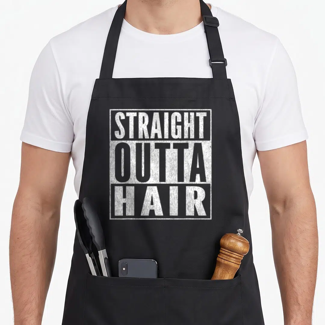 Straight hair apron - White distressed text reading STRAIGHT OUTTA HAIR stacked in a rectangle — shown on a black cotton canvas apron against a white background