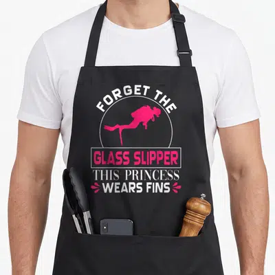 Scuba princess apron - Pink scuba diver silhouette with text forget glass slipper wears fins in white and pink — shown on a black cotton canvas apron against a white background