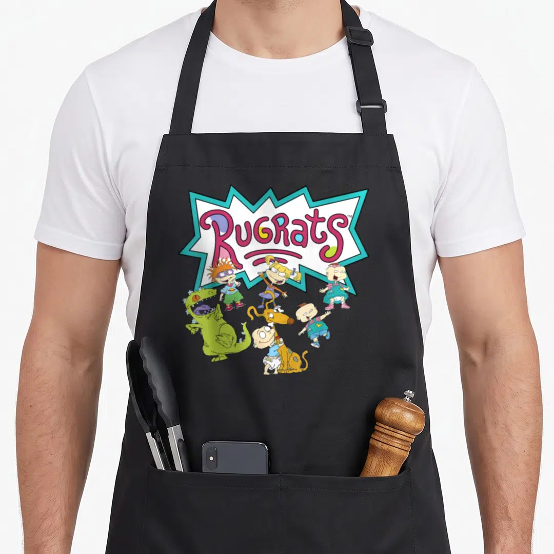 Play turning ninety apron - Rugrats logo in jagged burst with babies and green dinosaur in pink, blue, green — shown on a black cotton canvas apron against a white background
