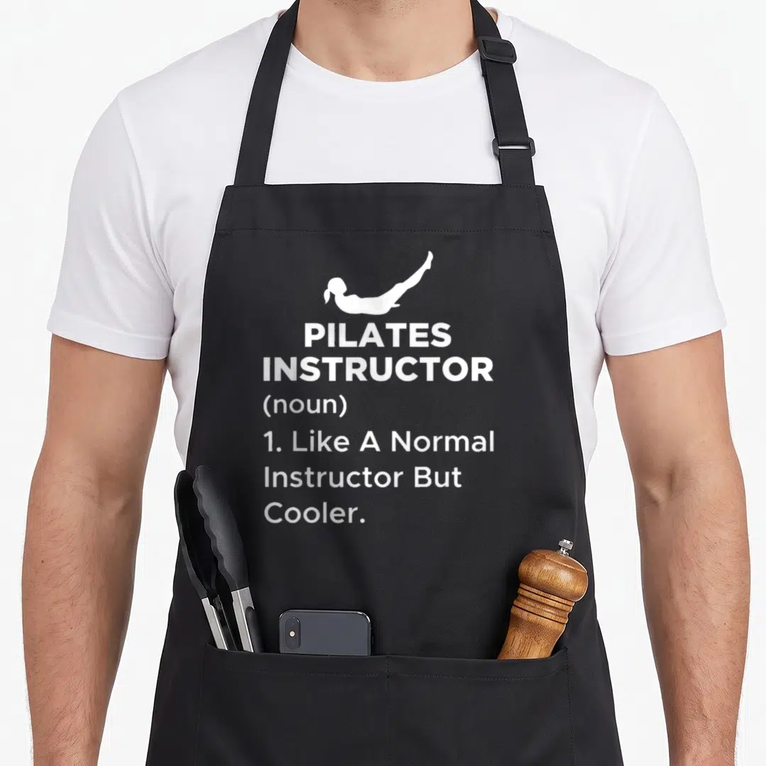 Pilate machine apron - White silhouette of pilates pose above definition text reading Like A Normal Instructor — shown on a black cotton canvas apron against a white background