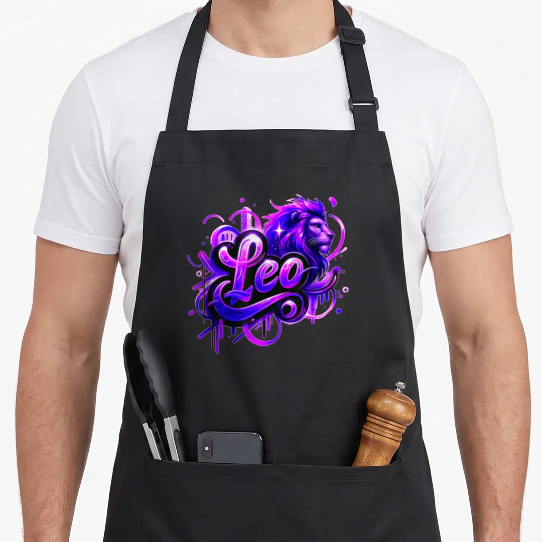Leo zodiac sign birthday apron - Cartoon lion head with Leo script text in purple, blue, and magenta with swirls — shown on a black cotton canvas apron against a white background