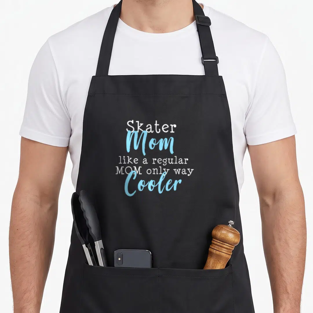 Skating figure mom apron - Stacked white and light blue text reading Skater Mom Cooler — shown on a black cotton canvas apron against a white background