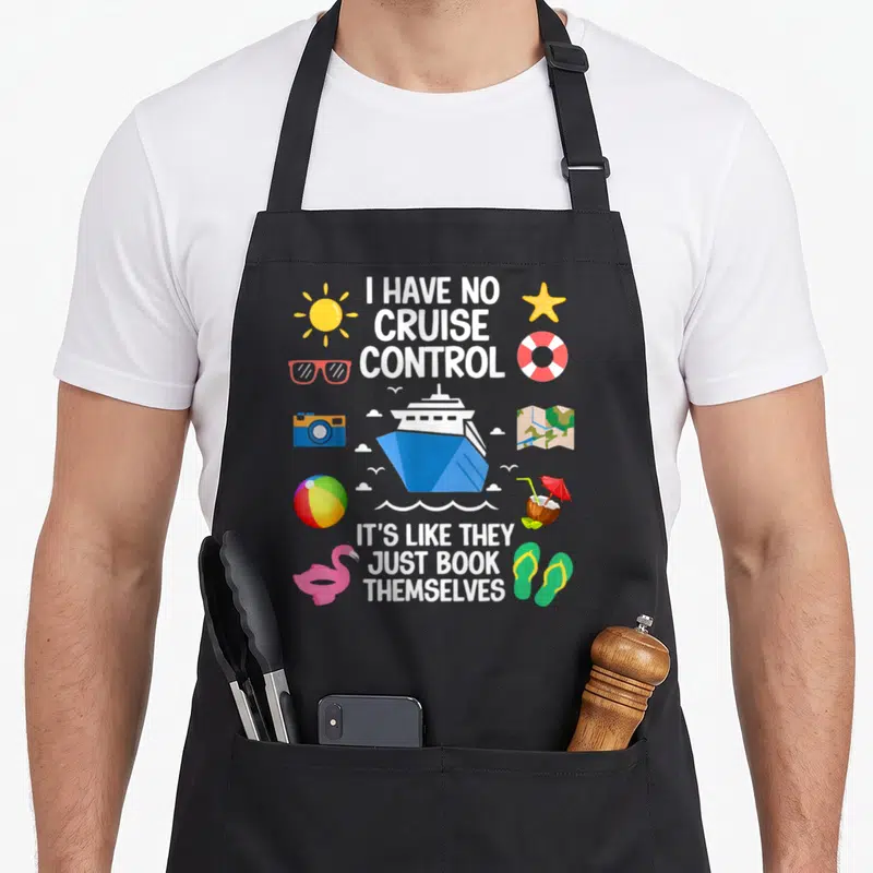Control crazy cruise apron - Cartoon cruise ship with vacation icons and text I HAVE NO CRUISE CONTROL IT'S LIKE THEY — shown on a black cotton canvas apron against a white background