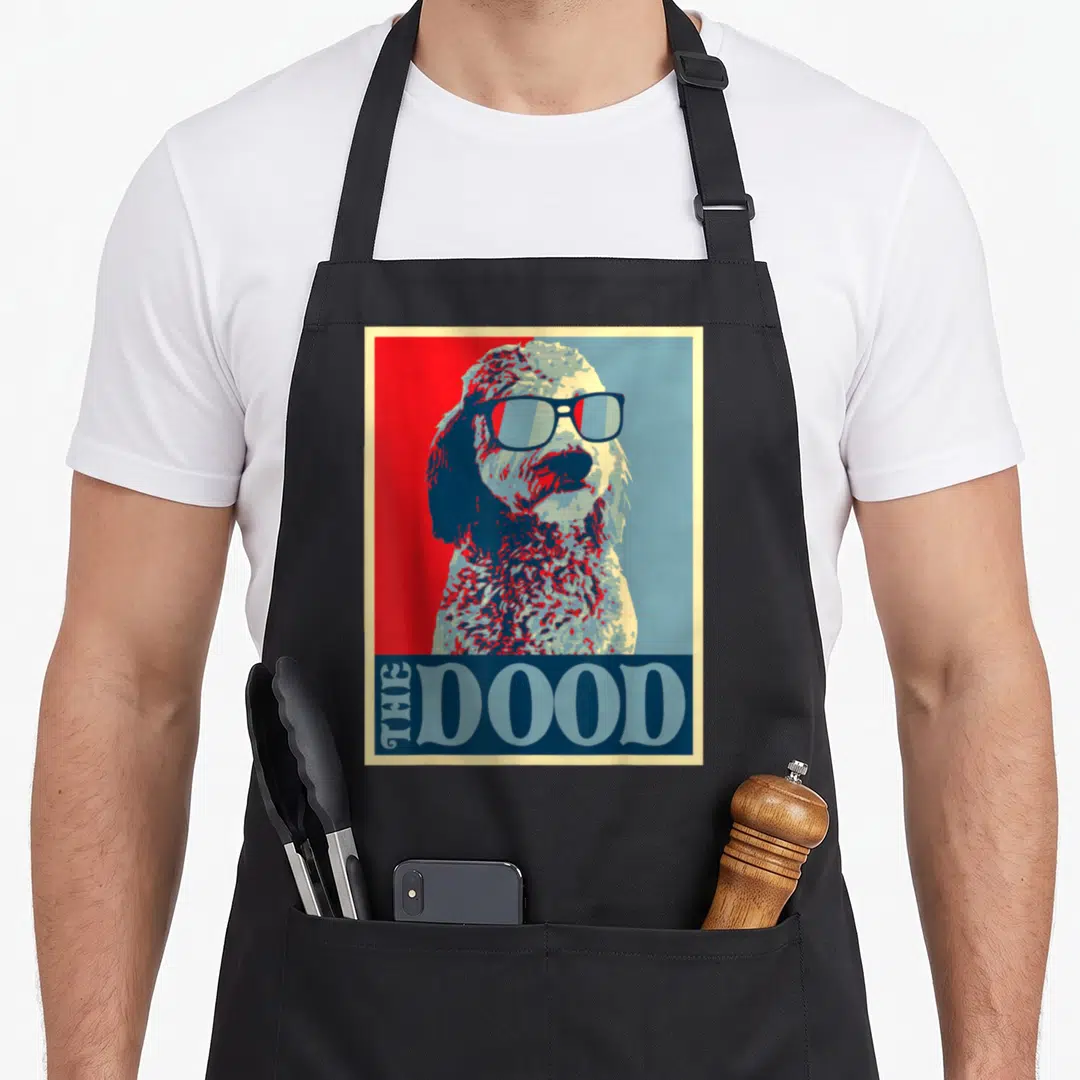Doodle goldendoodle apron - Retro dog wearing sunglasses with THE DOOD text on red and blue background — shown on a black cotton canvas apron against a white background