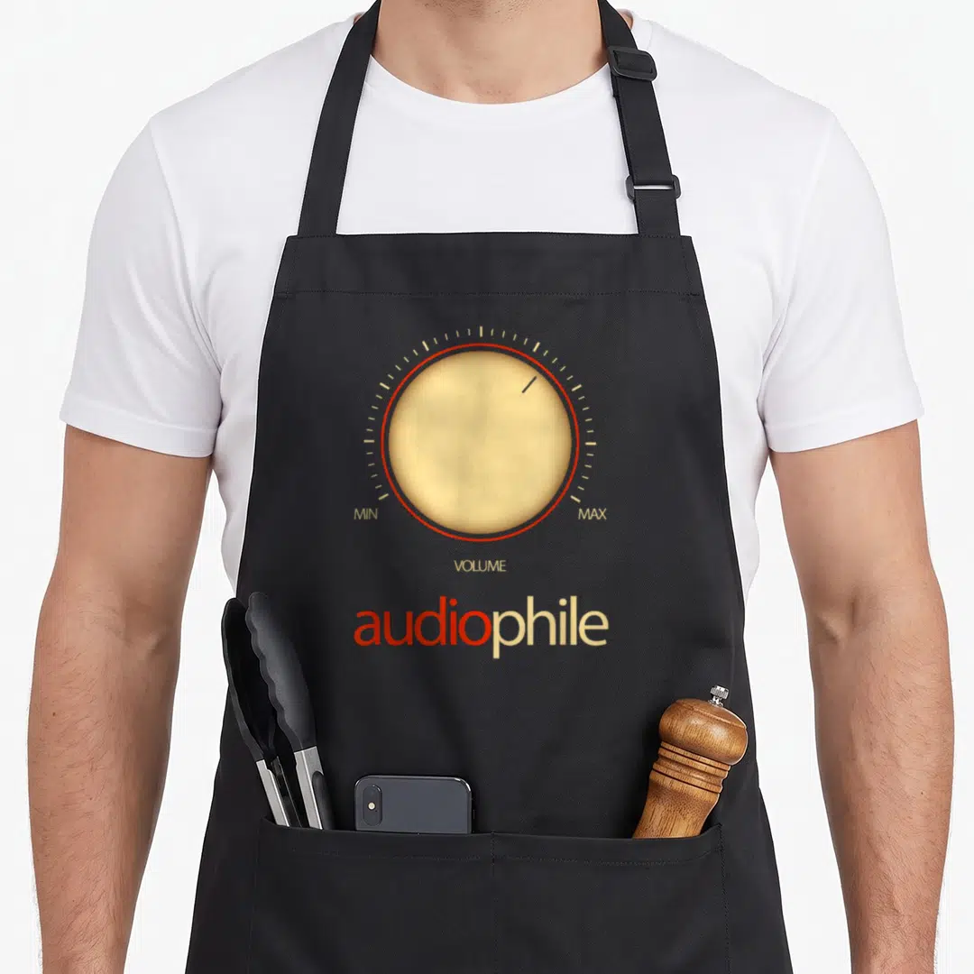 Amplifier music lover apron - Beige volume knob with red ring and audiophile text on black background — shown on a black cotton canvas apron against a white background
