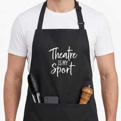 Sport theatre apron - White stacked text reading Theatre IS MY Sport on grey background — shown on a black cotton canvas apron against a white background