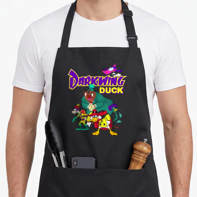 Cute darkwing duck apron - DARKWING DUCK text with purple plane and three cartoon characters in green and red — shown on a black cotton canvas apron against a white background