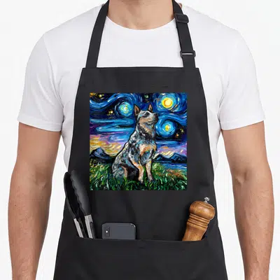 Blue dog apron - Realistic heeler dog sitting on green grass under a swirling blue starry night sky — shown on a black cotton canvas apron against a white background