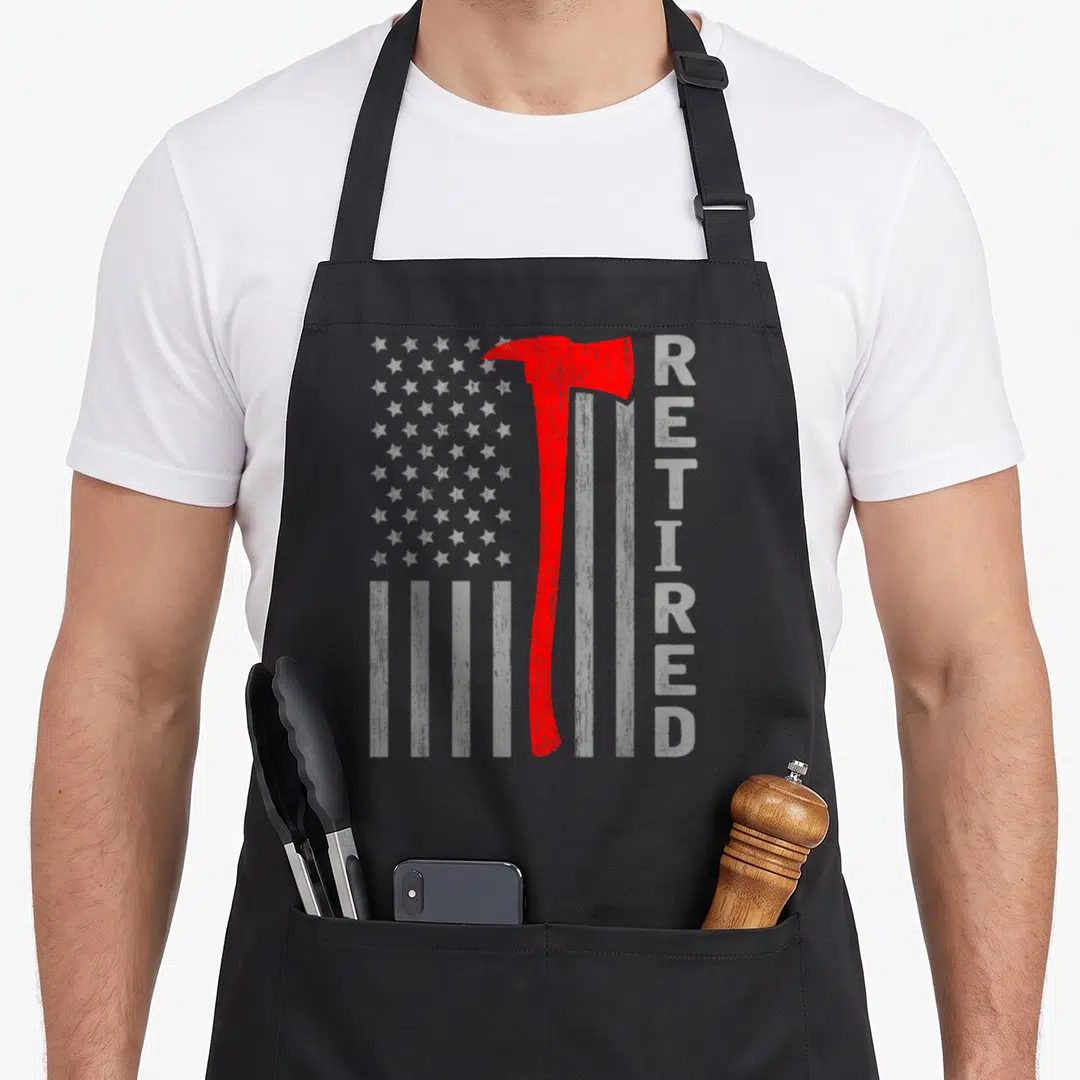 Outfit firefighter cooking apron - Red fire axe over white flag with vertical RETIRED text in distressed style — shown on a black cotton canvas apron against a white background