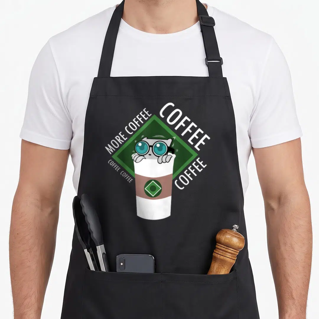 Coffee mushroom apron - Cartoon cat with glasses in coffee cup on green diamond with text — shown on a black cotton canvas apron against a white background