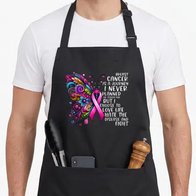 Journey breast cancer awareness aprons - Colorful butterfly with pink ribbon body and stacked text about fighting — shown on a black cotton canvas apron against a white background
