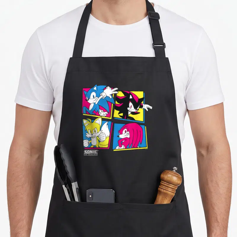Shadow hedgehog long apron - Sonic Shadow Tails Knuckles in colored square frames with Sonic The Hedgehog logo text — shown on a black cotton canvas apron against a white background