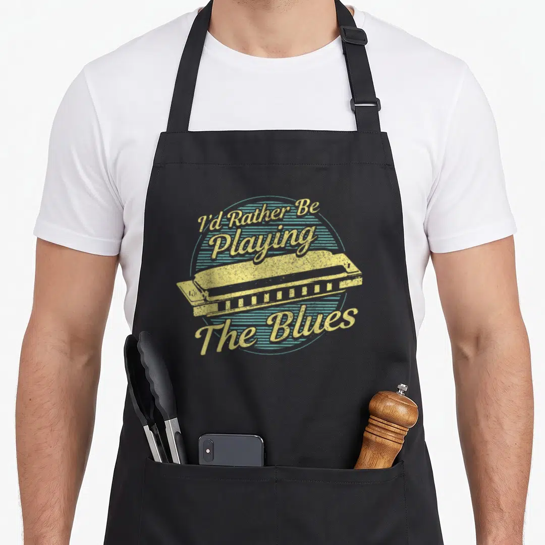 Blue harmonica apron - Yellow harmonica on blue striped circle with arched text I'd Rather Be Playing The Blues — shown on a black cotton canvas apron against a white background