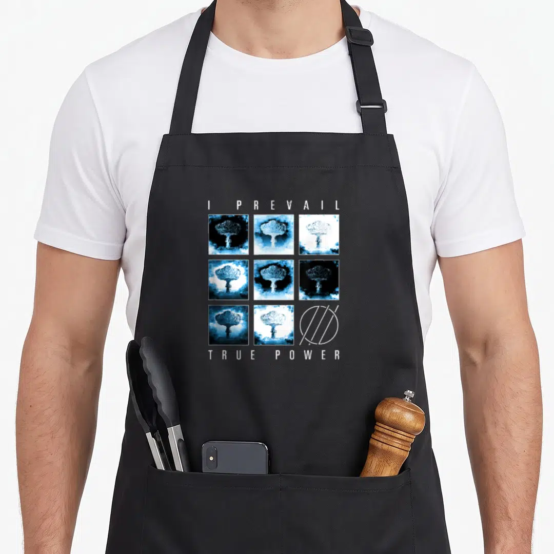 Prevail novelty apron - I Prevail True Power text with mushroom cloud grid and geometric circle logo in blue and white — shown on a black cotton canvas apron against a white background