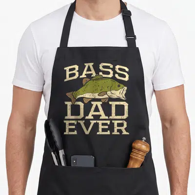 Bass father day apron - Distressed beige text reading Bass Dad Ever around an olive green bass fish illustration — shown on a black cotton canvas apron against a white background