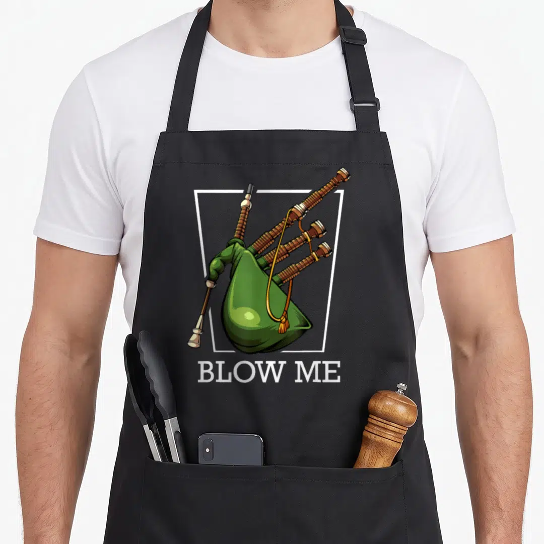 Blow game aprons - Cartoon green bagpipes in white frame above BLOW ME text — shown on a black cotton canvas apron against a white background