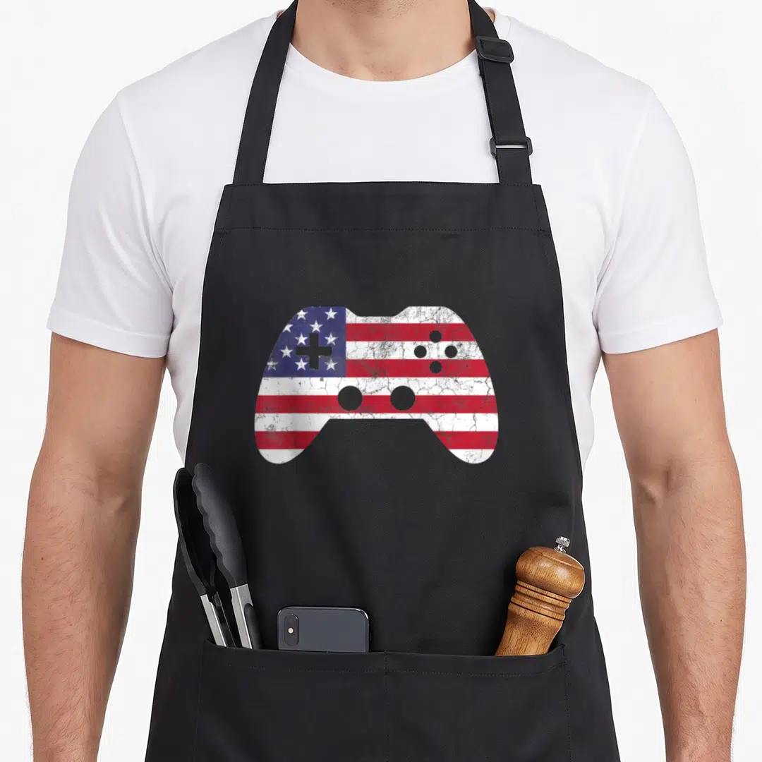 Video 4th of july apron - Distressed game controller shape filled with red white blue flag pattern — shown on a black cotton canvas apron against a white background