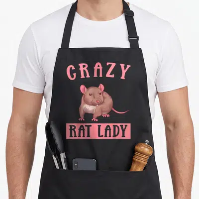 Owner rat animal apron - Arched pink GRAZY text over brown cartoon rat with pink ears, gray belly, and pink rectangle — shown on a black cotton canvas apron against a white background