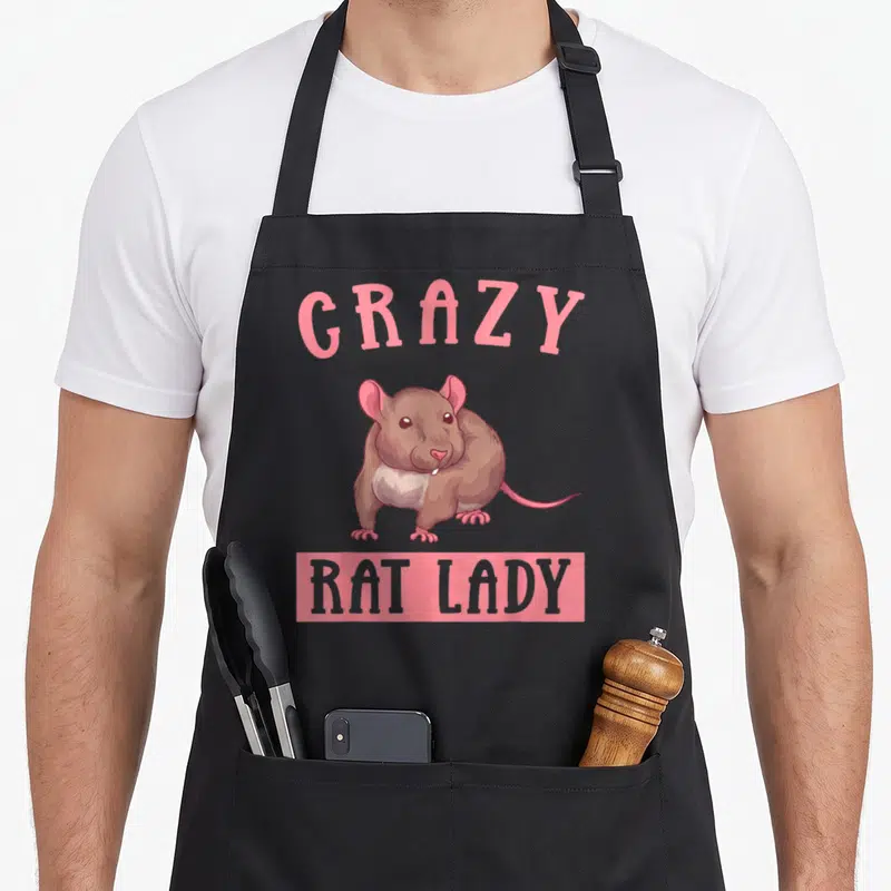 Owner rat animal apron - Arched pink GRAZY text over brown cartoon rat with pink ears, gray belly, and pink rectangle — shown on a black cotton canvas apron against a white background
