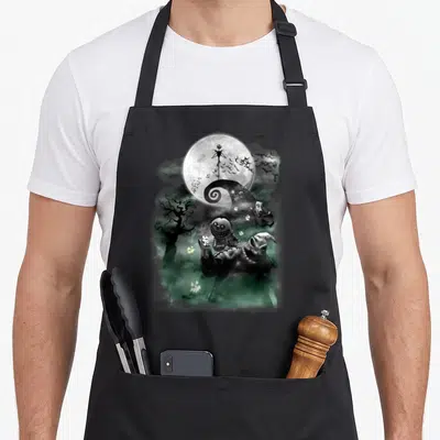 Jack barrel apron - Jack Skellington silhouette on spiral hill with Oogie Boogie holding dice in green mist — shown on a black cotton canvas apron against a white background