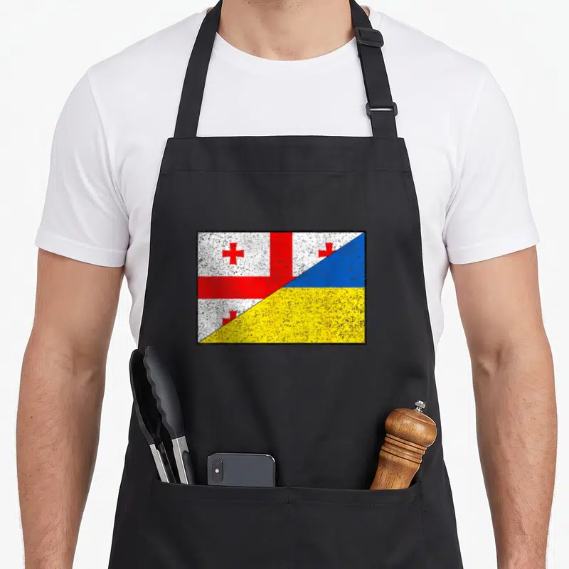 Georgia ukrainian aprons - Two flags merged diagonally in red white blue and yellow with distressed texture — shown on a black cotton canvas apron against a white background