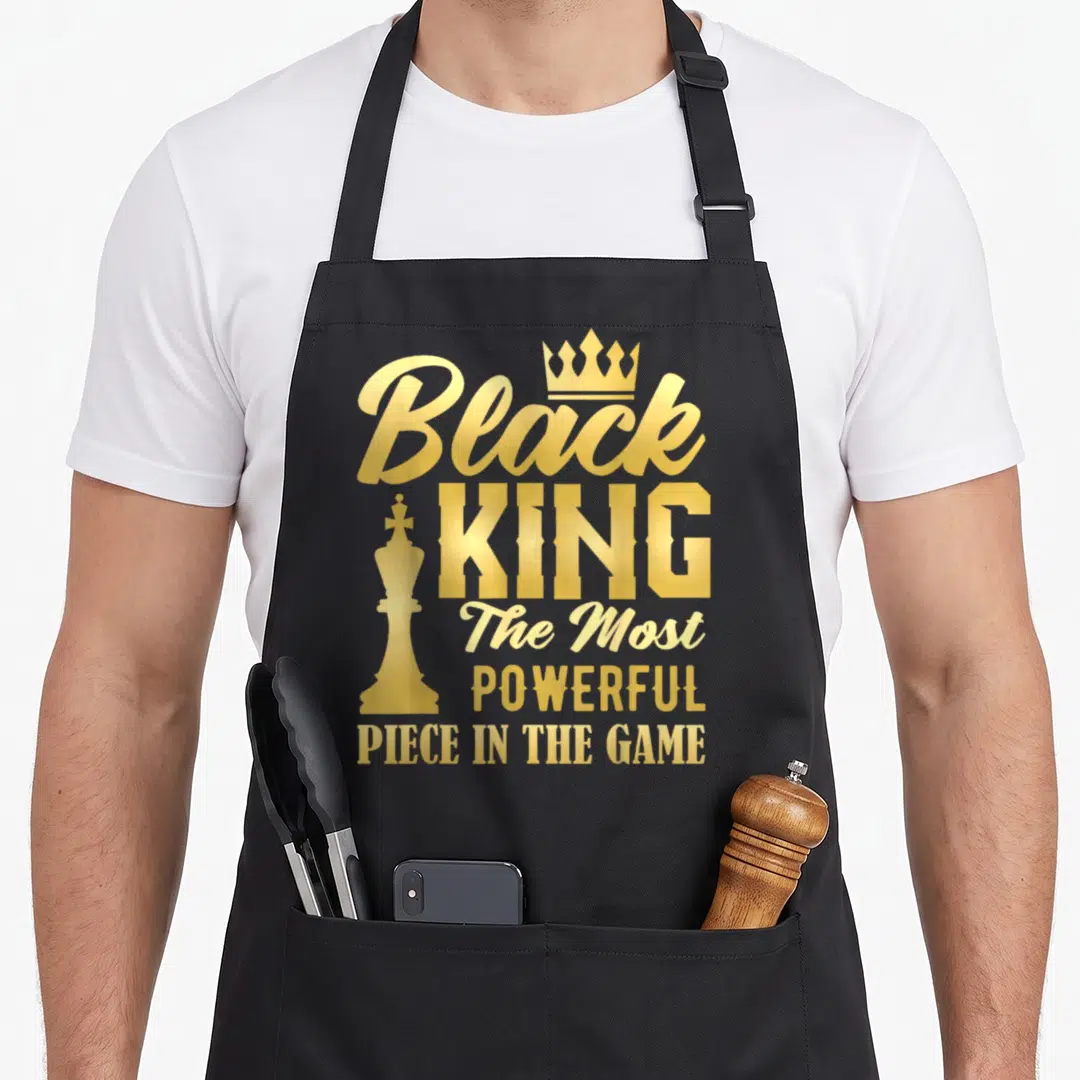 Game king apron - Gold Black King typography with chess piece and crown on black background — shown on a black cotton canvas apron against a white background