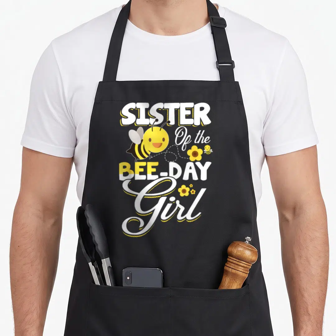 Sister bee aprons - Stacked SISTER Of the BEE-DAY Girl text with cartoon bees and yellow flowers — shown on a black cotton canvas apron against a white background