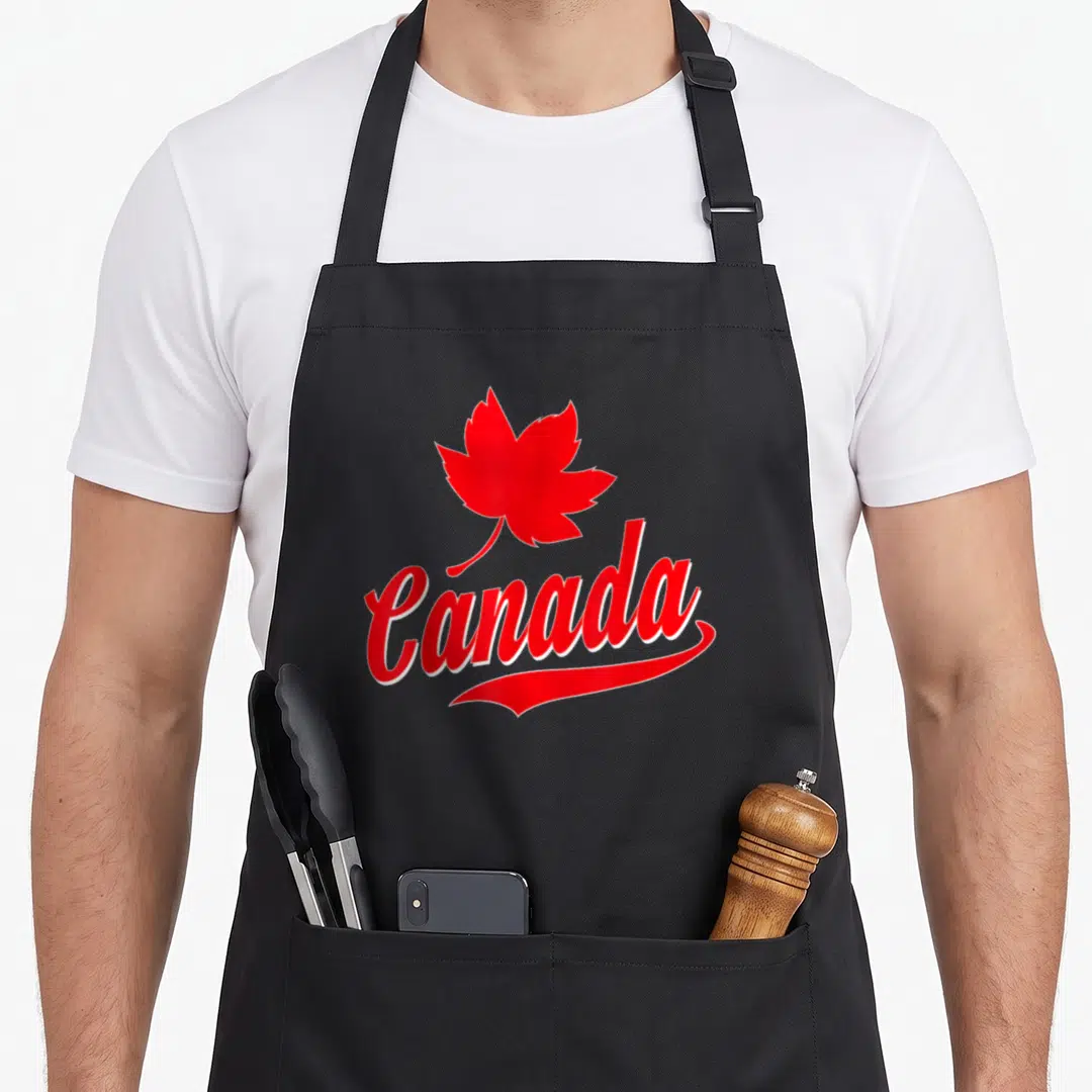 Leaf canada canadian aprons - Red maple leaf above red Canada script on black bib apron — shown on a black cotton canvas apron against a white background