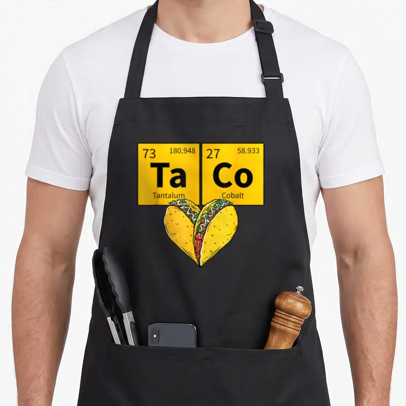 Taco table apron - Two yellow periodic table squares above heart-shaped tacos in cartoon style — shown on a black cotton canvas apron against a white background