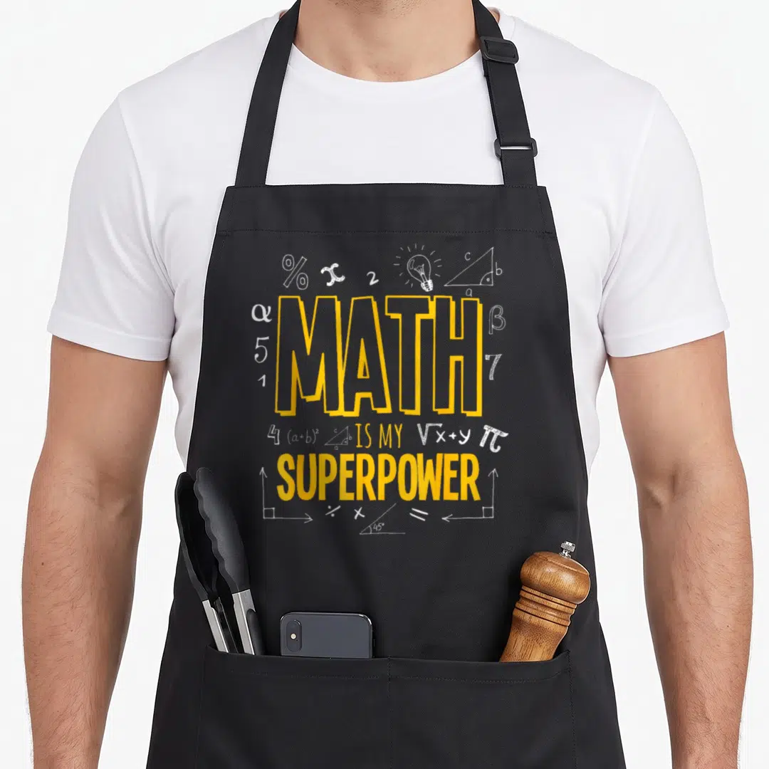 Superpower math dad apron - Yellow MATH IS MY SUPERPOWER text with white light bulb triangle and math symbols — shown on a black cotton canvas apron against a white background