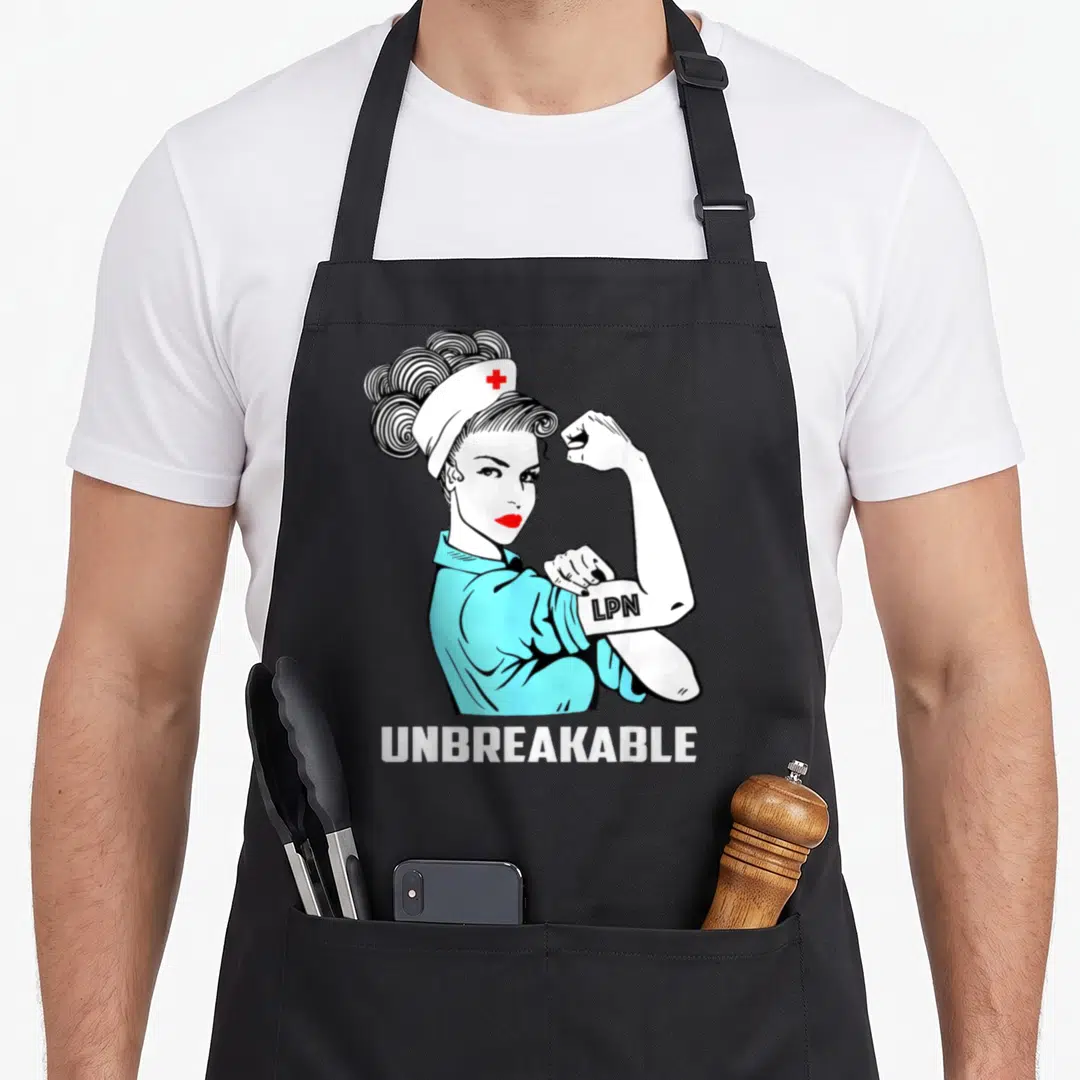 Unbreakable nurse apron - Cartoon nurse flexing arm with LPN on sleeve and UNBREAKABLE text below — shown on a black cotton canvas apron against a white background
