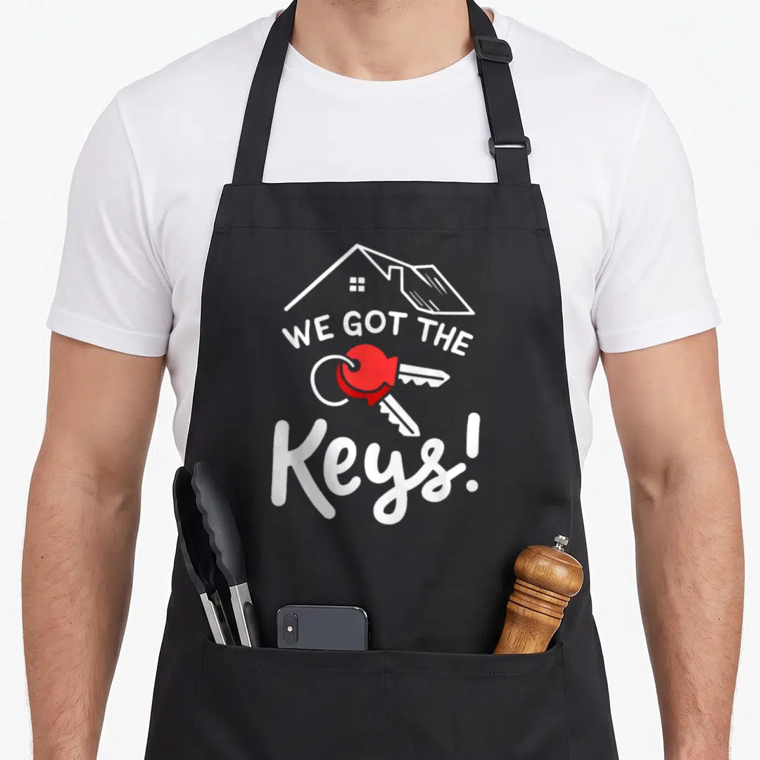 Key novelty apron - White house outline with WE GOT THE Keys! text and two keys on a red ring — shown on a black cotton canvas apron against a white background