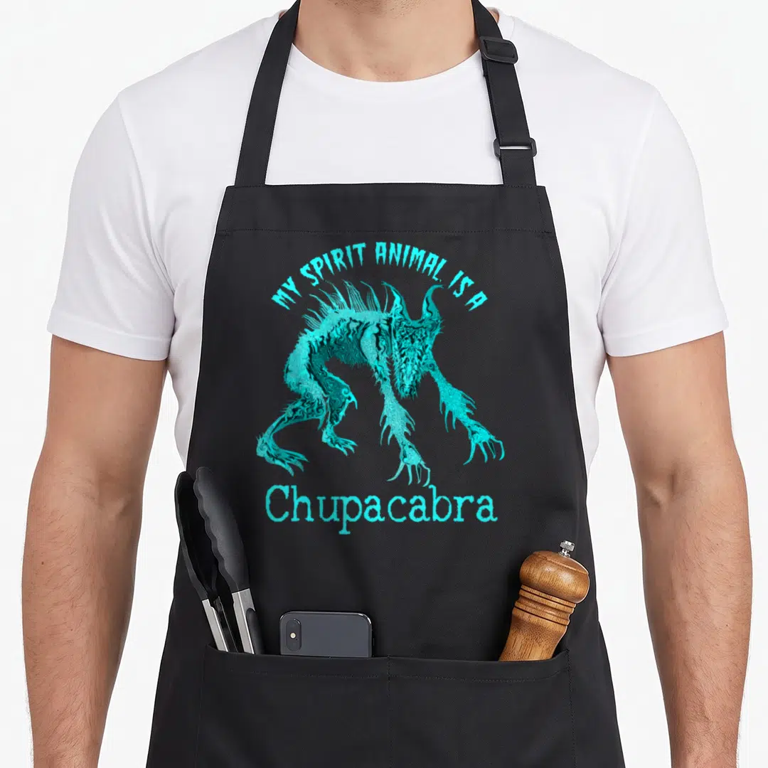 Chupacabra animal apron - Cyan chupacabra creature with MY SPIRIT ANIMAL IS A text arched above — shown on a black cotton canvas apron against a white background
