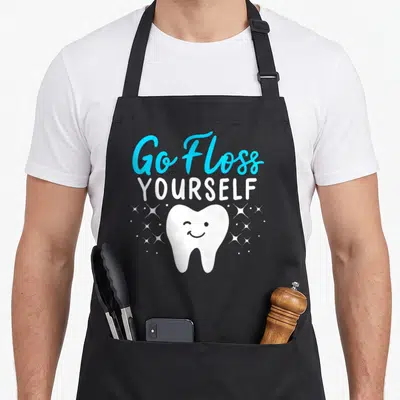 Dental assistant dentist apron - Blue and white Go Floss Yourself text above a winking cartoon tooth surrounded — shown on a black cotton canvas apron against a white background