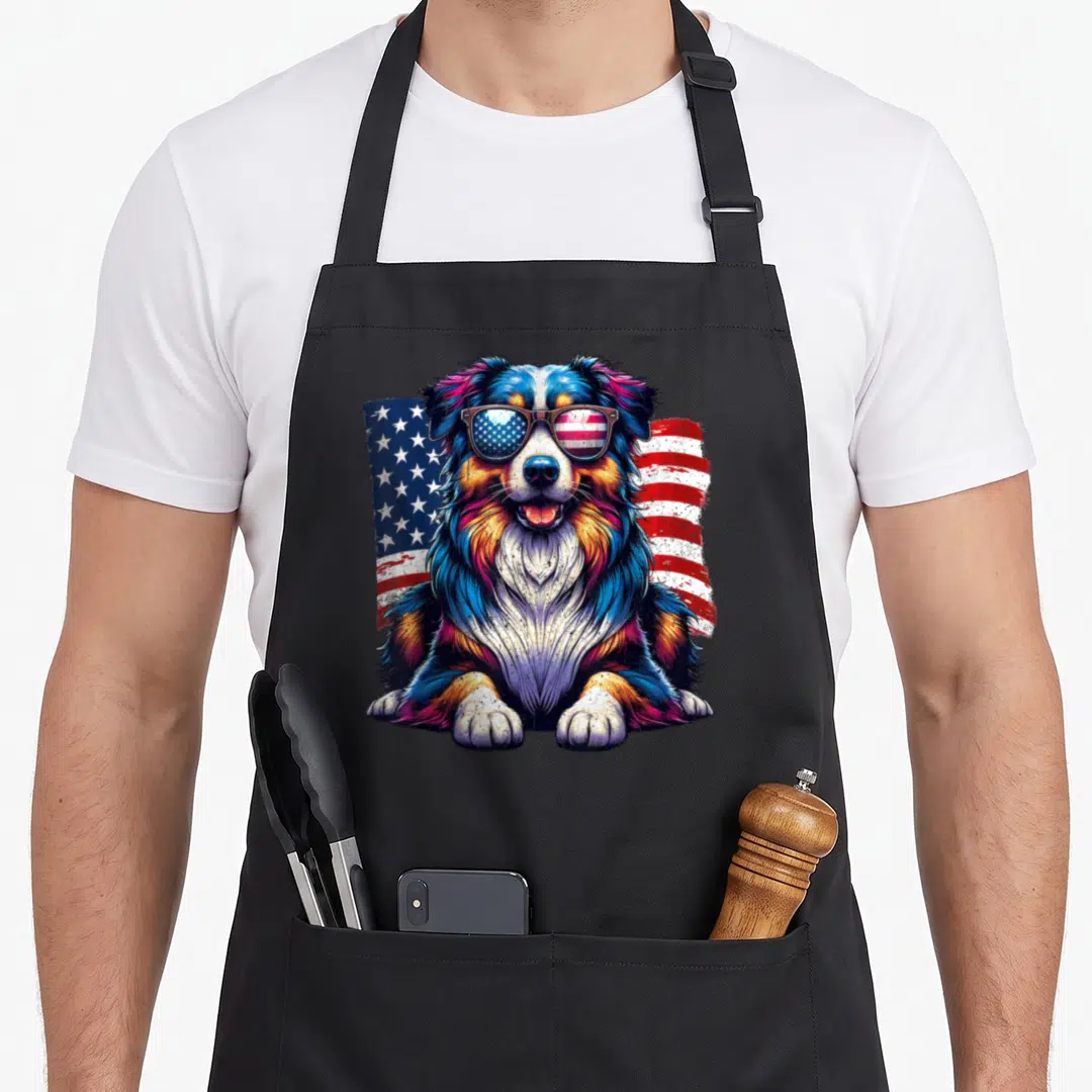 4th australian aprons - Cartoon dog with sunglasses reflecting stars and stripes in blue red white and orange — shown on a black cotton canvas apron against a white background