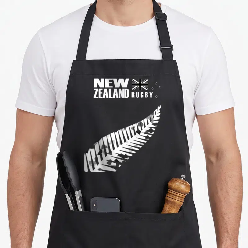 Rugby new zealand apron - Camo silver fern and New Zealand Rugby text on black bib — shown on a black cotton canvas apron against a white background