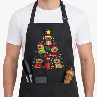 Pekingese christmas tree apron - Five brown dogs in Christmas tree shape with yellow star, red gift, and dog heart — shown on a black cotton canvas apron against a white background